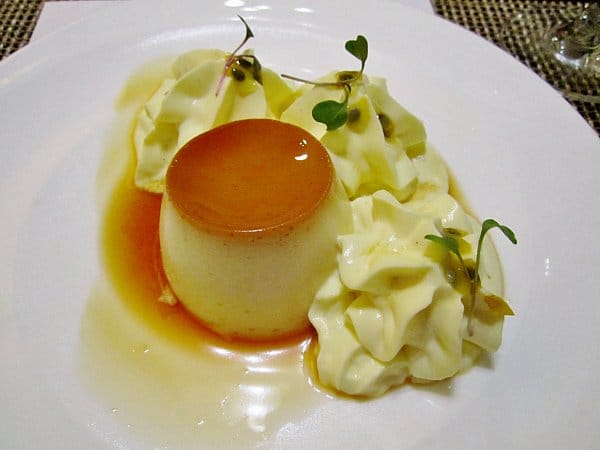 a small flan surrounded by rosettes of cream on a white plate