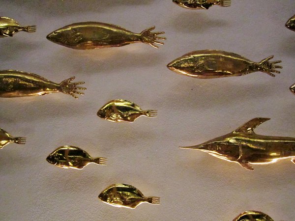 closeup of gold fish figures with hands as tails on a white wall