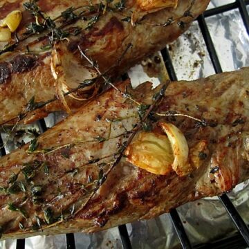 closeup of two roasted pork tenderloins on a roasting rack