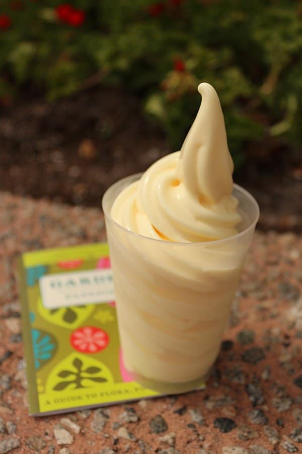 A closeup of a dole whip frozen dessert in a tall clear cup