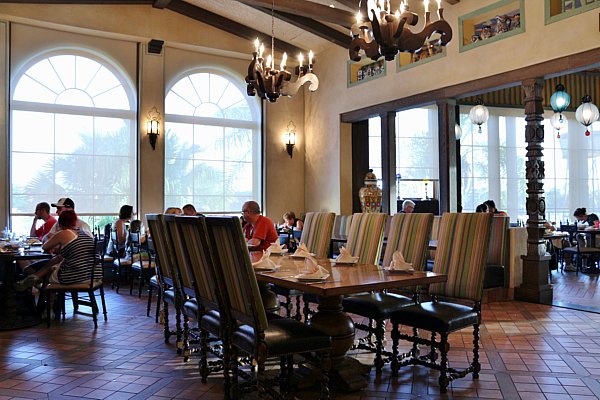 A restaurant dining room with tables, chairs, and large windows