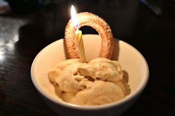 a bowl of ice cream with a churro and yellow birthday candle stuck into the top