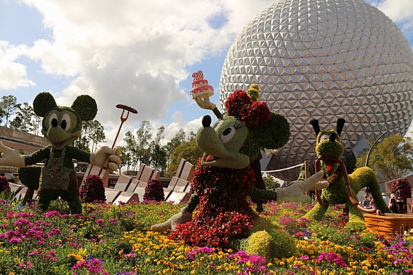 a topiary of Mickey, Minnie, and Pluto in front of Spaceship Earth at Epcot