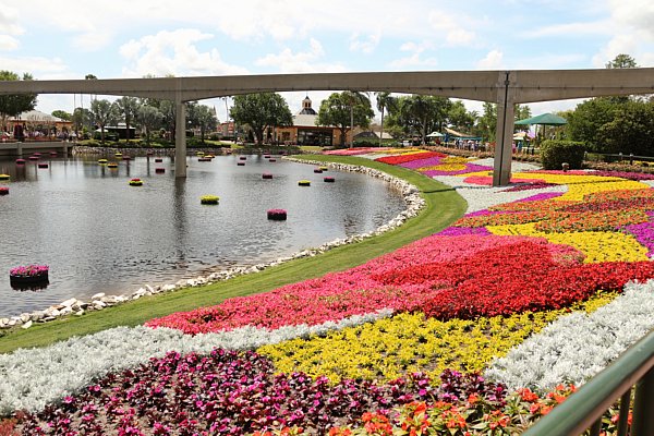 A bridge over a body of water surrounded by colorful gardens