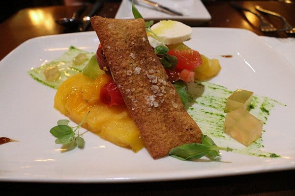 a salad with yellow heirloom tomatoes and mozzarella on a white plate