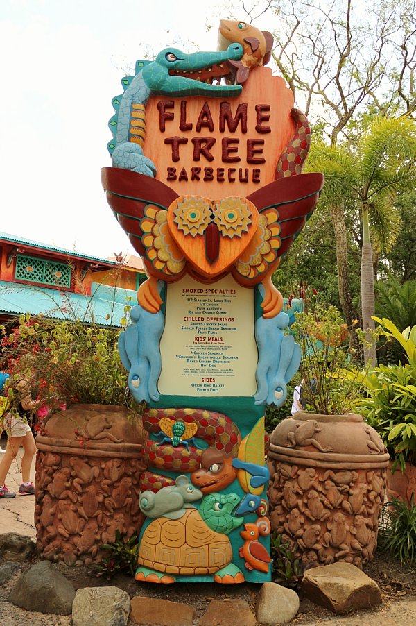 a colorful sign that says Flame Tree Barbecue with a menu underneath