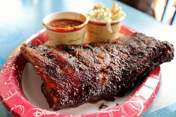 barbecue ribs with cups of baked beans and coleslaw on a paper plate
