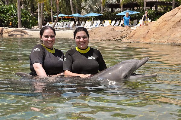 two women posting with a dolphin in the water