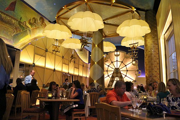 a group of people dining in a restaurant with yellow parachutes hanging from the ceiling