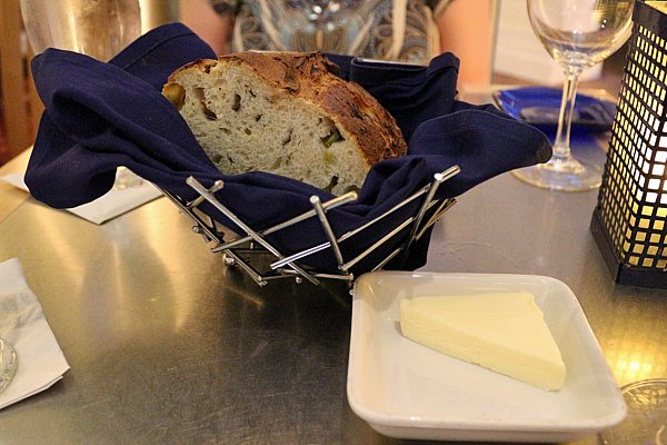 a basket of bread and a triangle of butter on a white plate