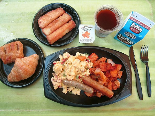 A bunch of breakfast foods on black plates on a light green table