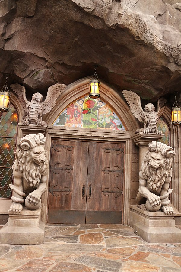 large wooden doors with stone statues on either side and a colorful mosaic over the top