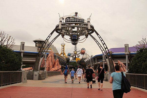 A group of people walking toward the galactic looking entrance to Tomorrowland