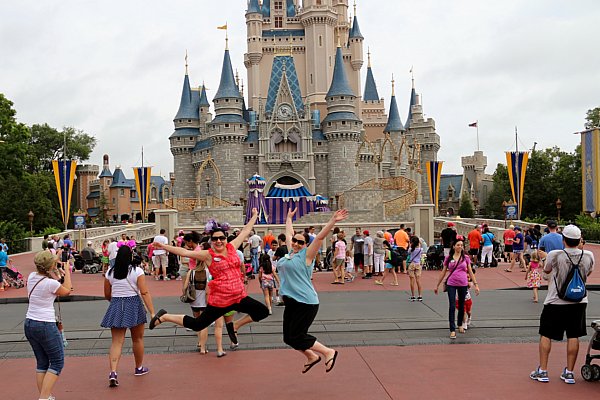 two women jumping in front of Cinderella\'s castle