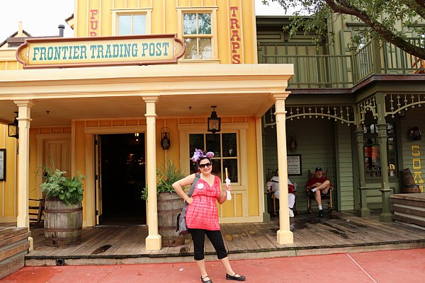 A woman holding a churro standing in front of a building