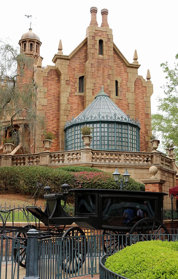 a black hearse in front of a creepy looking stone building