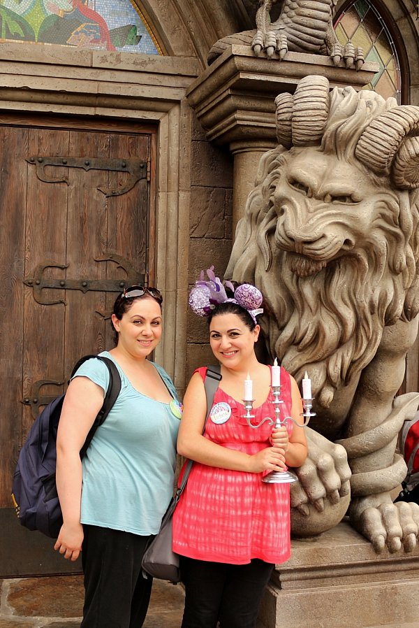 two women standing in front of a stone statue of a beast