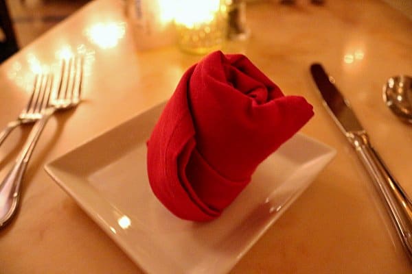 a red cloth napkin shaped to look like a rose