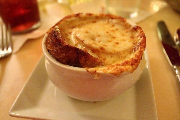 French onion soup topped with melted cheese in a white bowl