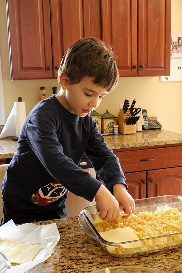 A boy arranging slices of cheese into a glass baking dish