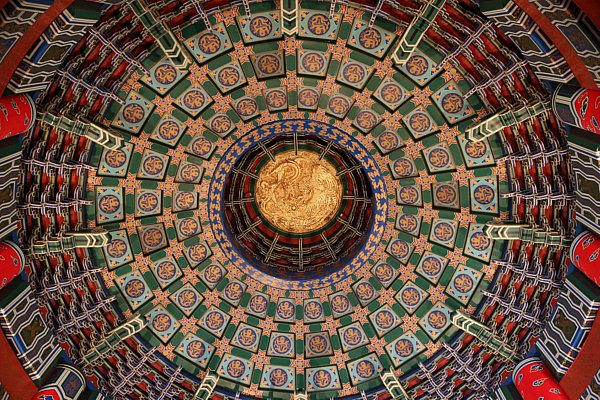 view looking up at a colorful tiled circular ceiling with a gold center