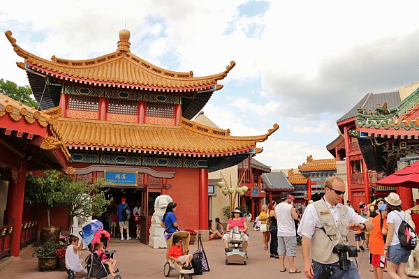 A group of people walking in front of buildings in the China Pavilion of Epcot