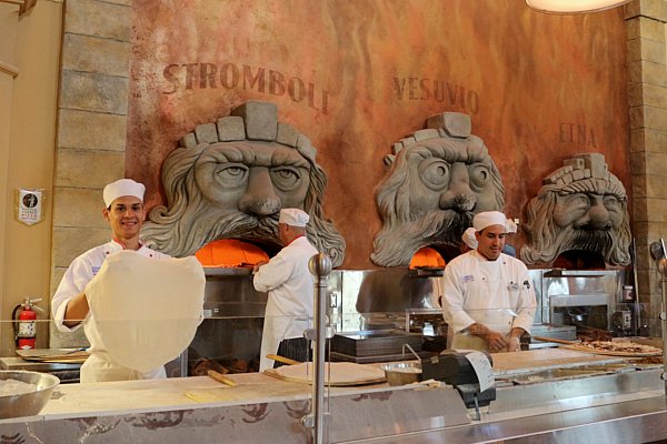 A group of people making pizzas in a professional kitchen