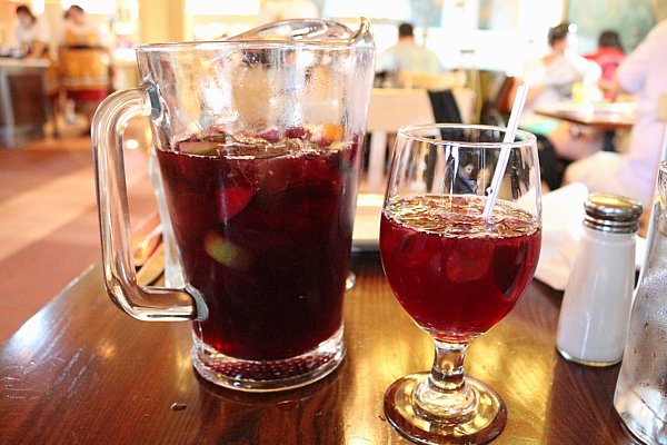 a pitcher and a glass of red sangria on a wooden table