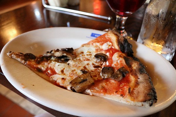 A slice of mushroom pizza on a white plate