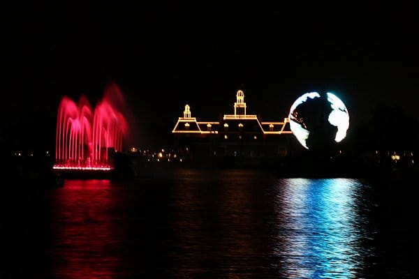 a red fountain and a glowing globe over a large body of water at night