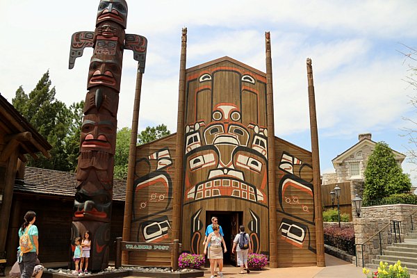 A group of people in front of a totem pole and native painted building