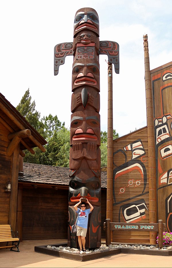 A woman posing in front of a totem pole