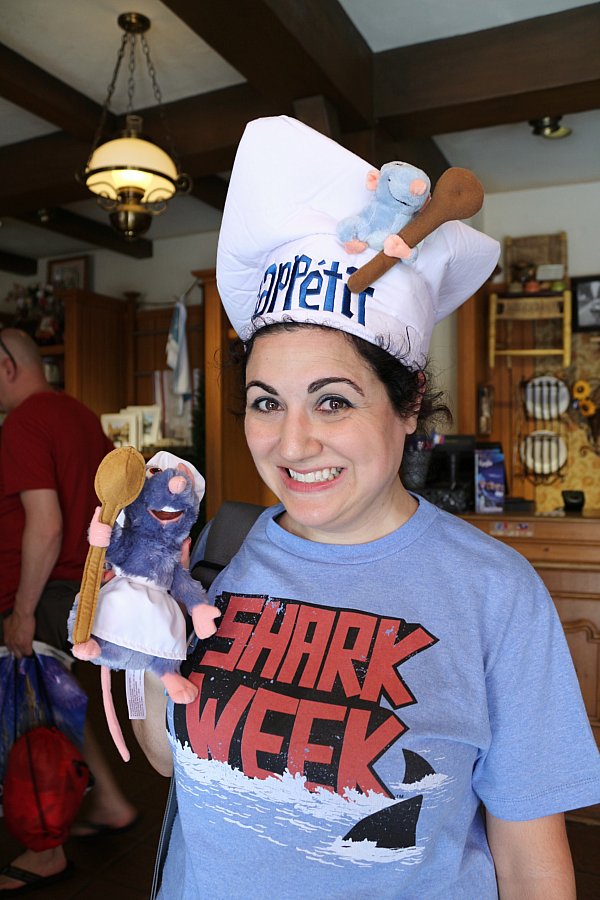 A woman wearing a chef\'s hat and holding a Remy from Ratatouille stuffed rat