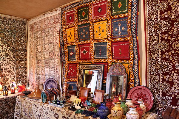 colorful tapestries hanging from walls behind tables covered with pottery for sale