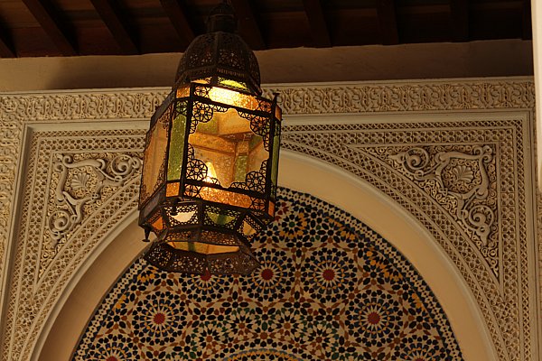 a hanging lantern in front of a colorful mosaic wall