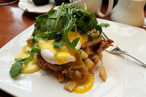 a closeup of pulled pork hash topped with a poached egg with yolk oozing out