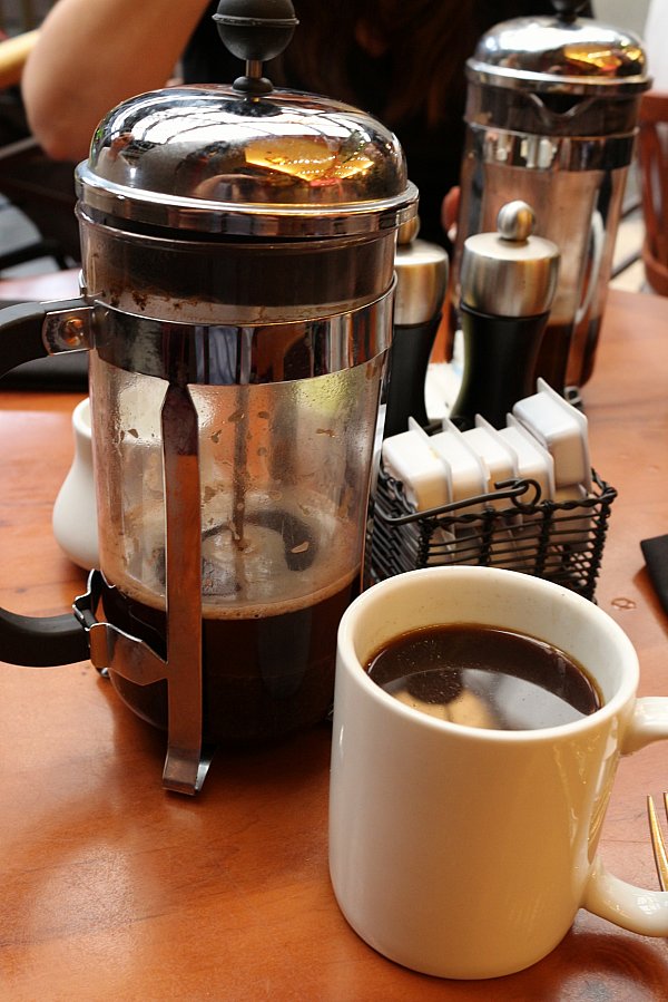 A French press and a cup of coffee on a table