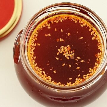 overhead view of a jar of chile oil with sesame seeds floating on top