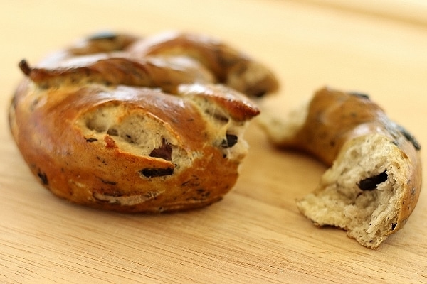 olive and garlic soft pretzel with a piece broken off