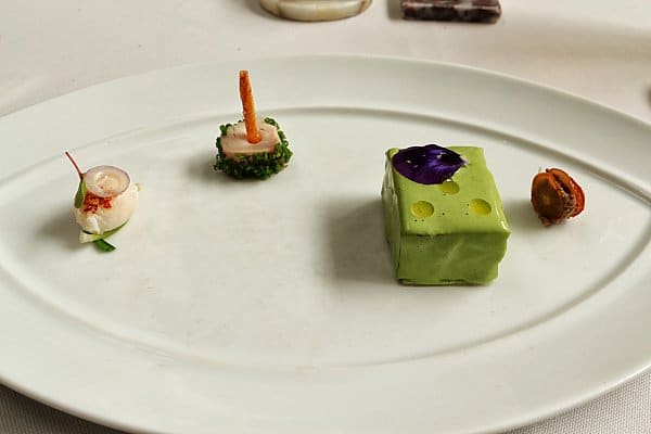 small bites of colorful food sparsely arranged on a white plate