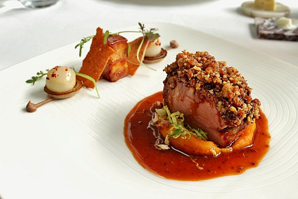 an artfully plated piece of pork with brown sauce on a white plate