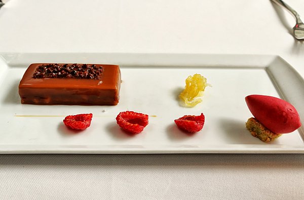 a long brown bar with raspberry halves on a white plate