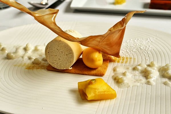 an artfully plated dessert with mango ice cream and a crispy sugar decoration