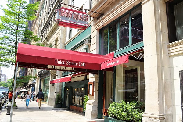 exterior of Union Square Cafe with red awning and white writing