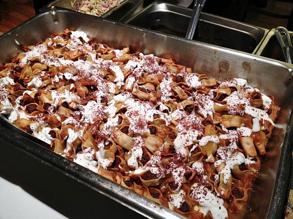 a large metal tray filled with food topped with yogurt sauce