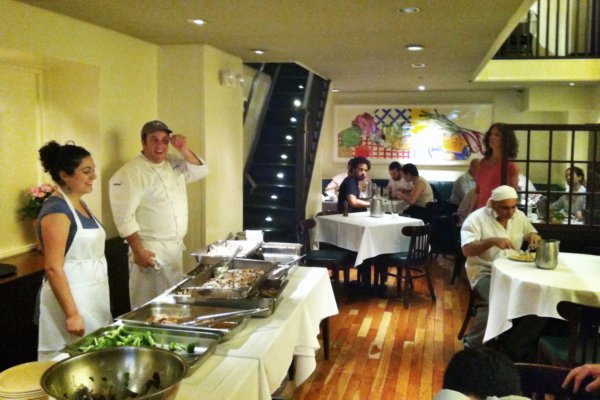 a man and woman standing behind a buffet table in a restaurant dining room