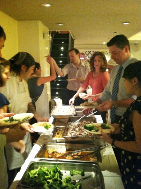 A group of people standing around a table filling food from a buffet