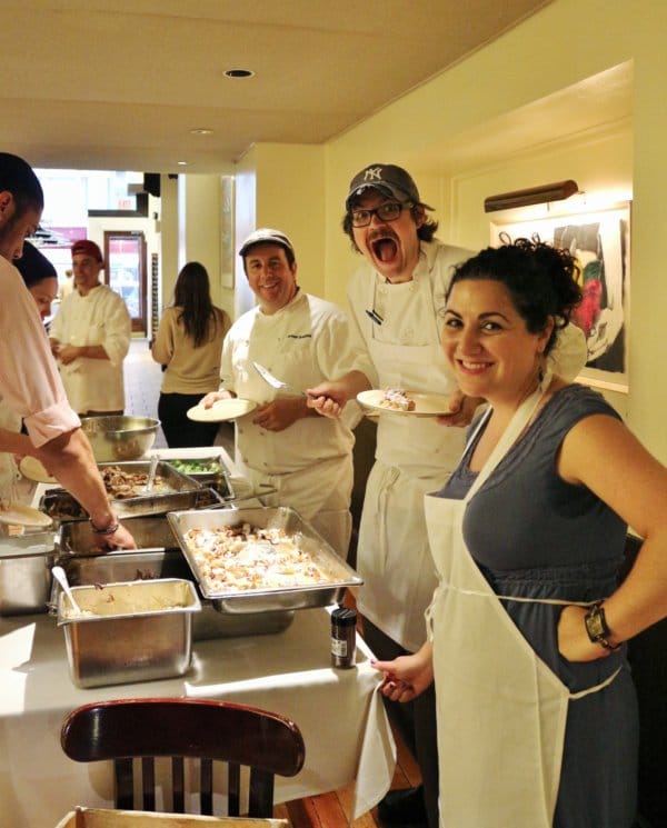 A group of people standing in a restaurant next to a buffet line of food