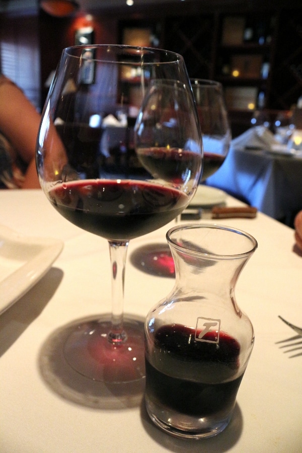 a glass of red wine with a small carafe of wine next to it