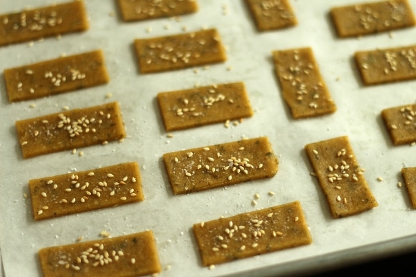 A closeup of unbaked rectangular crackers on a baking sheet